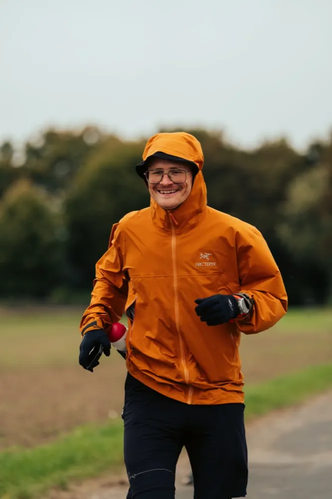 Pierre Biege läuft in orangefarbener Jacke über einen Feldweg