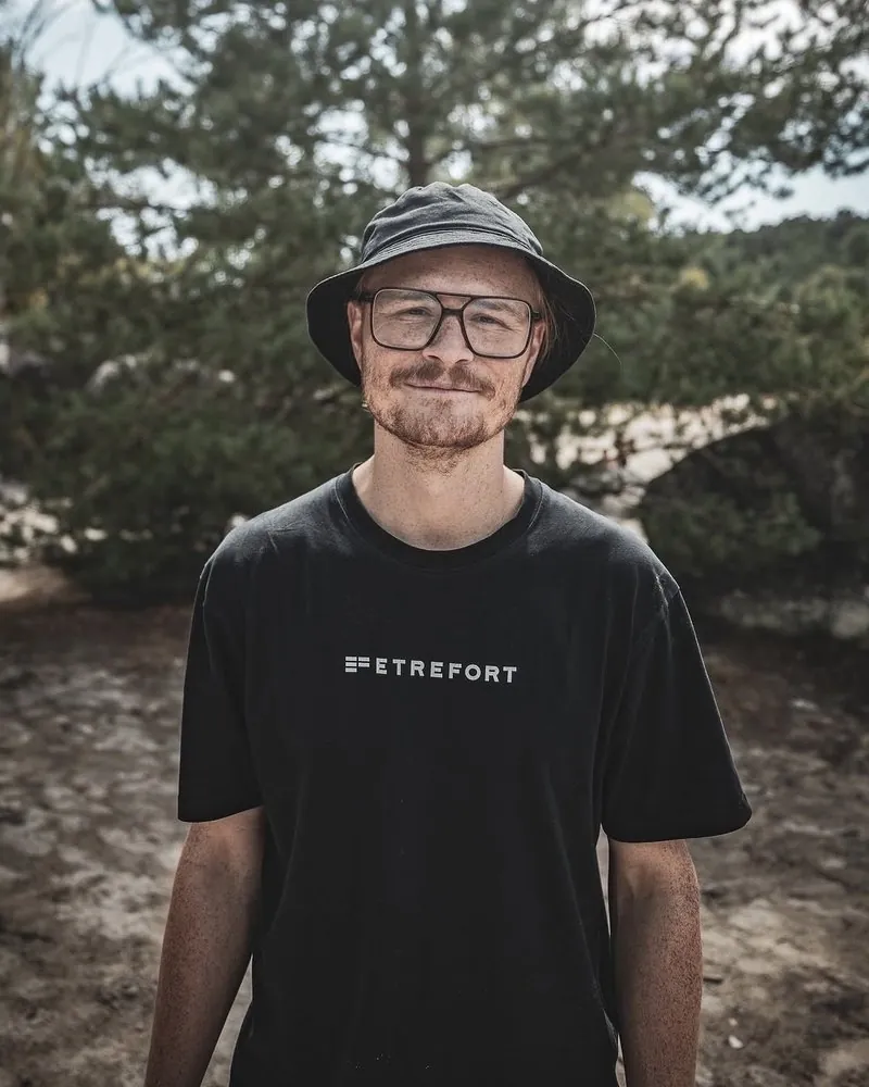 Porträt von Pierre Biege im Wald, mit Hut und Brille